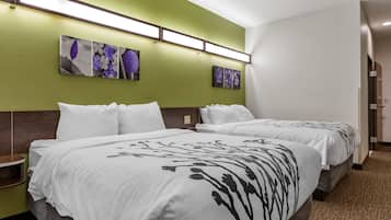 A hotel room with two beds, green walls, and artwork on the wall.