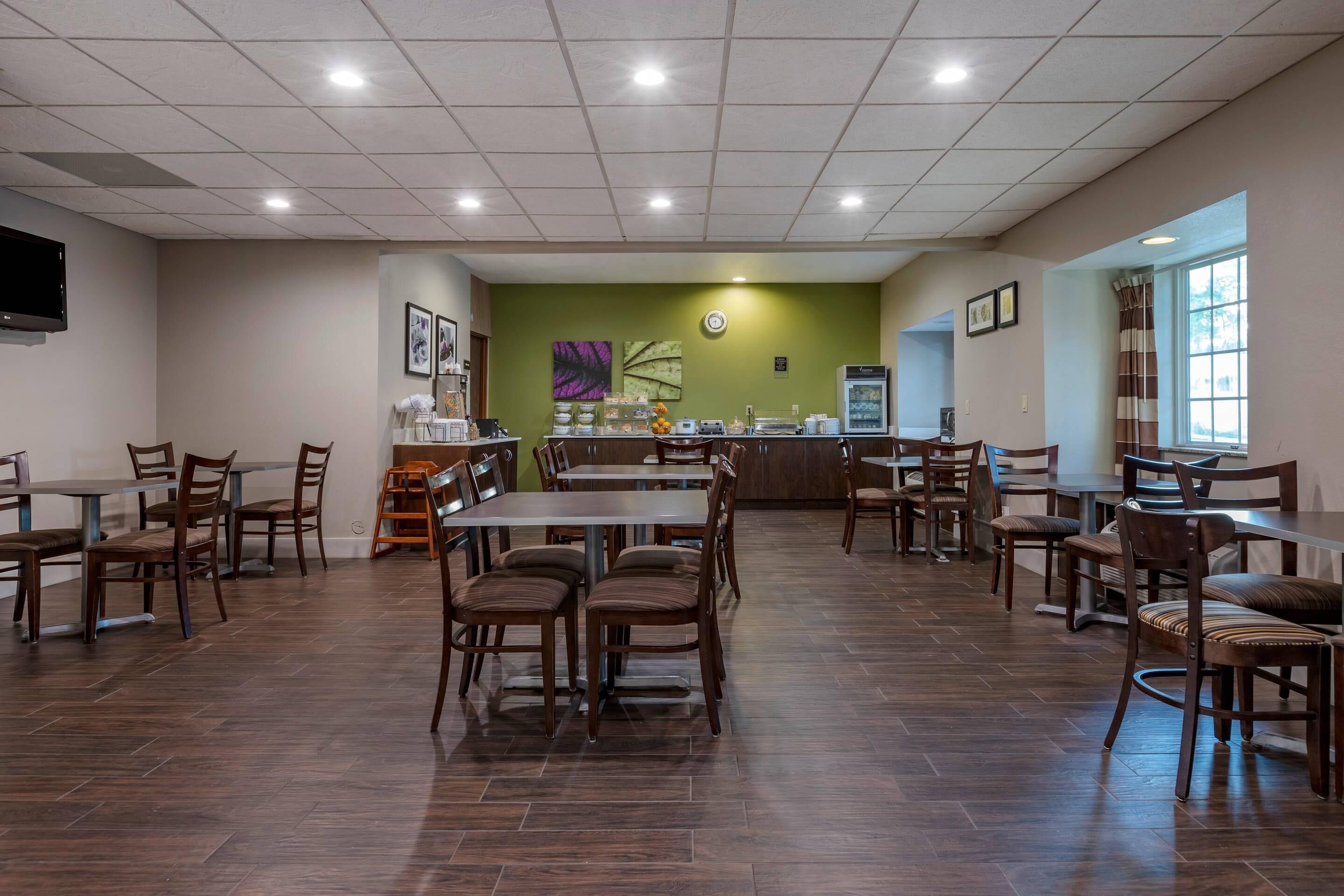 A restaurant with multiple tables and chairs, a counter with a display, and a clock on the wall.