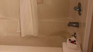 A bathroom with a bathtub, a shower curtain, and a towel rack with a towel.