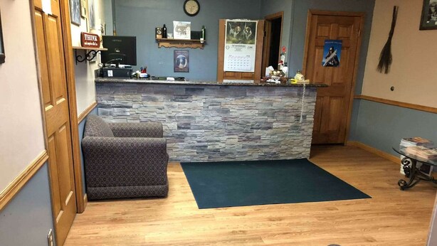 A reception area with a stone counter, a couch, and a wooden floor.
