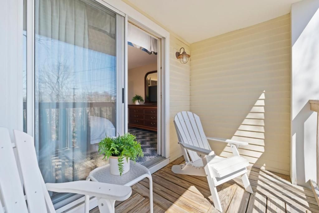 A balcony with a table, two chairs, and a potted plant.