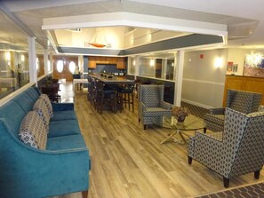 A modern interior with a dining area, sofas, and patterned chairs. - The Grand Hotel (Ogunquit)