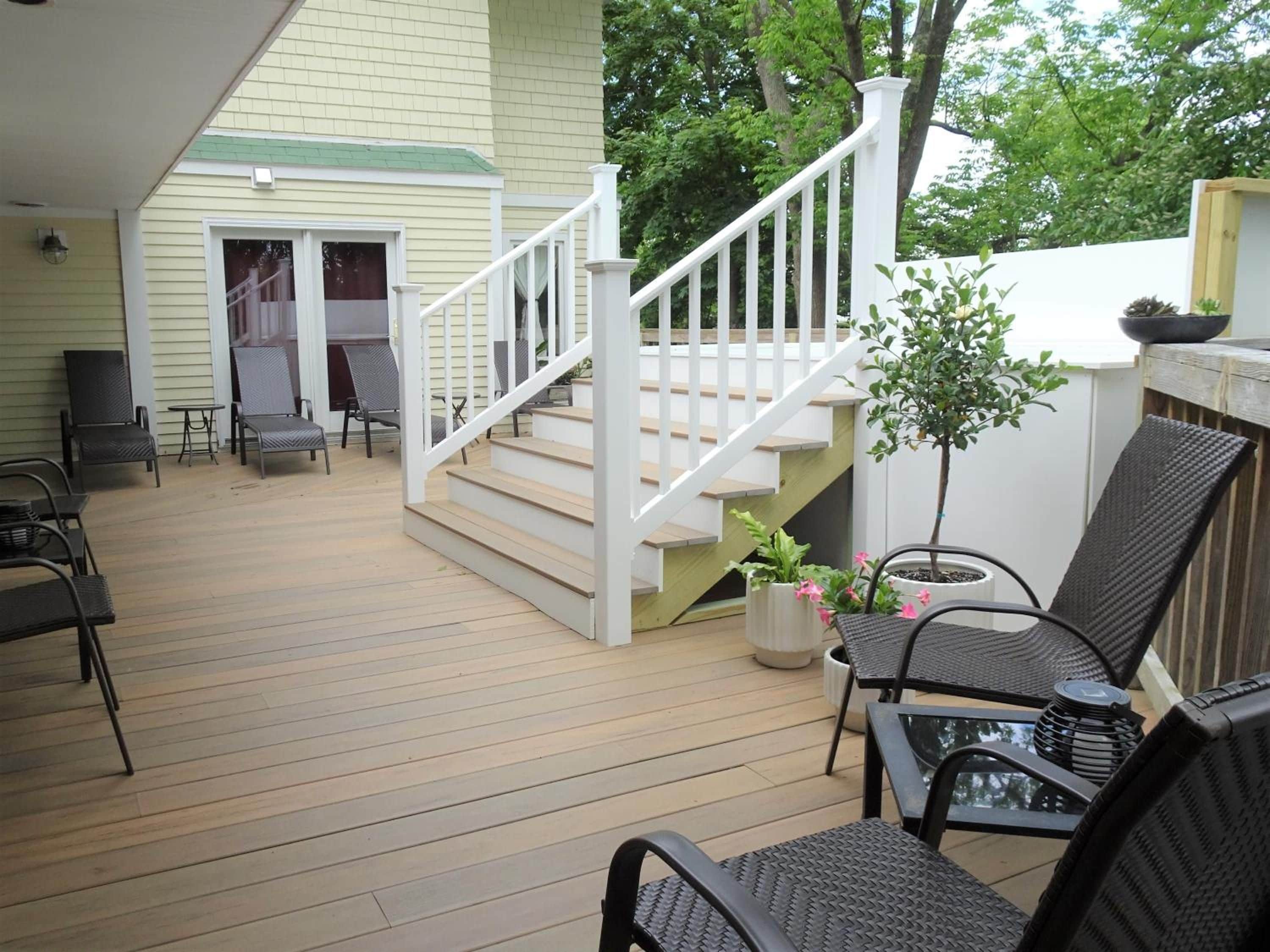 Une terrasse couverte avec un escalier, du mobilier d’extérieur et une plante en pot.