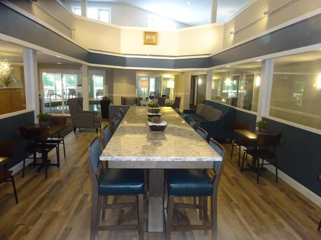 A spacious dining area with a long table, blue cushioned seating, and a view of the outdoors through large windows.