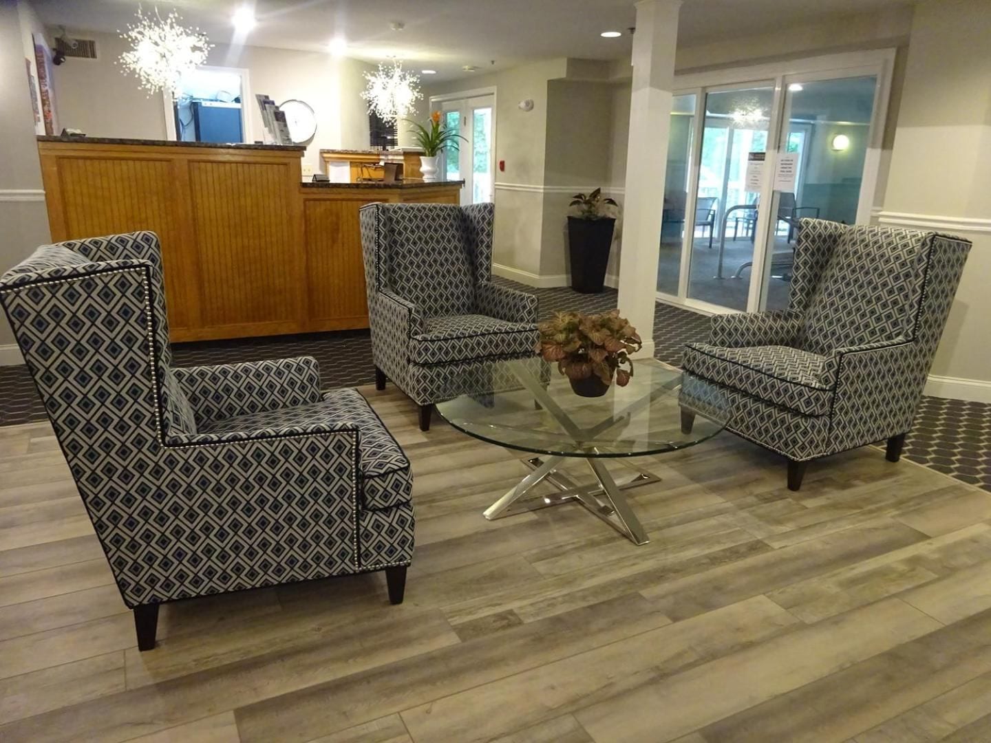 Un área de recepción con sillones estampados, una mesa de centro de vidrio y un mostrador de recepción.