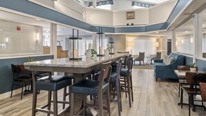 Un comedor amplio, con varios niveles, una isla central, taburetes de bar y un sofá azul.