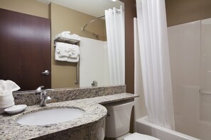 A bathroom with a granite sink, a mirror, a towel rack, a shower curtain, and a toilet.