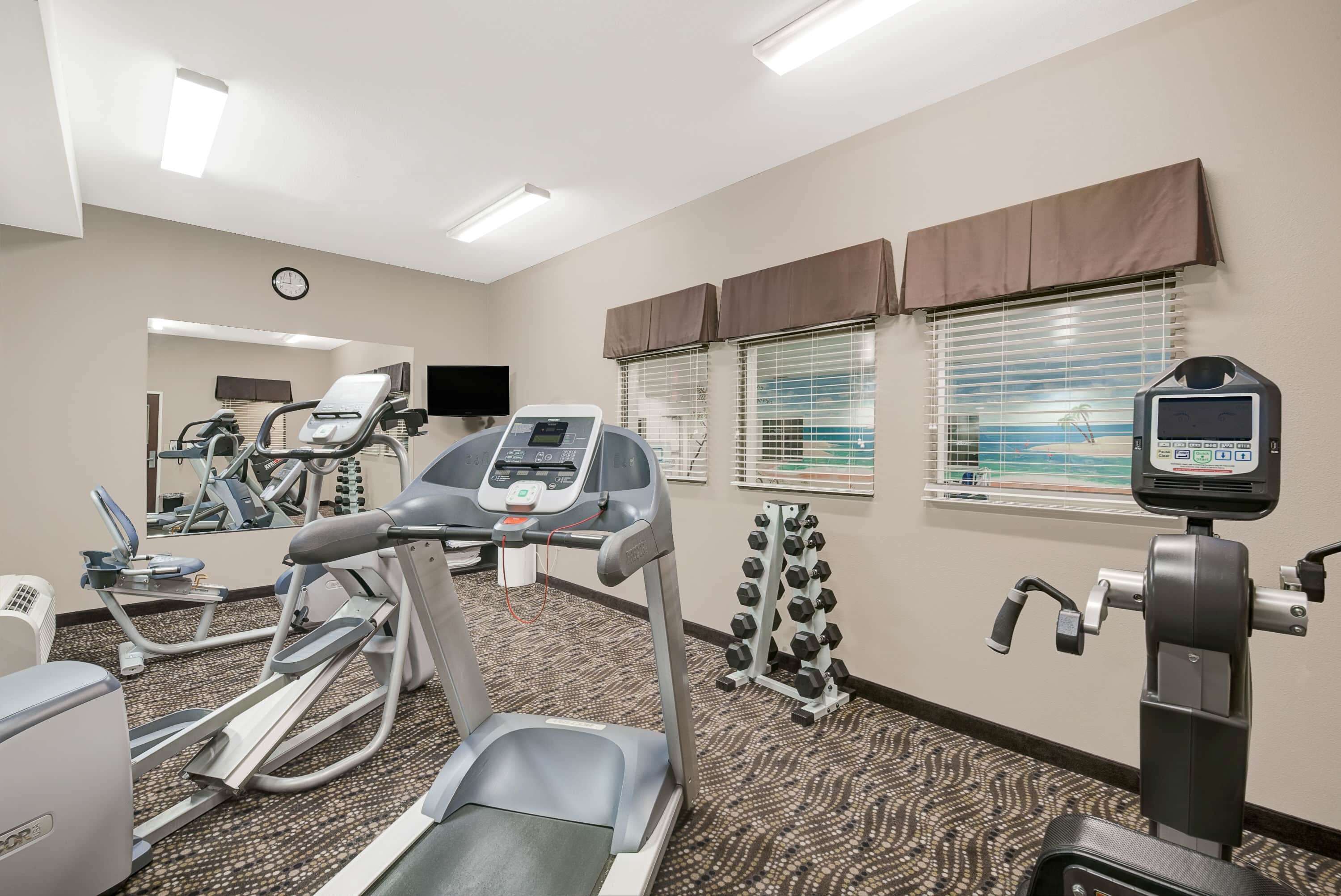 A hotel gym with treadmills, elliptical machines, and weight machines.