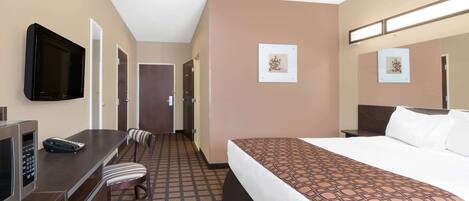 A hotel room with a bed, a desk with a telephone, a television, and a chair.