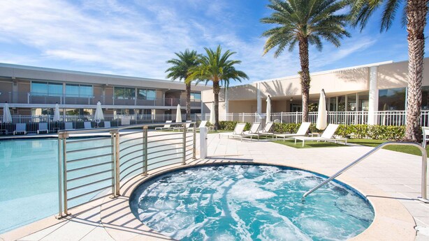 A pool area with a hot tub, lounge chairs, and palm trees. - Ramada by Wyndham Venice Hotel Venezia (Venice)