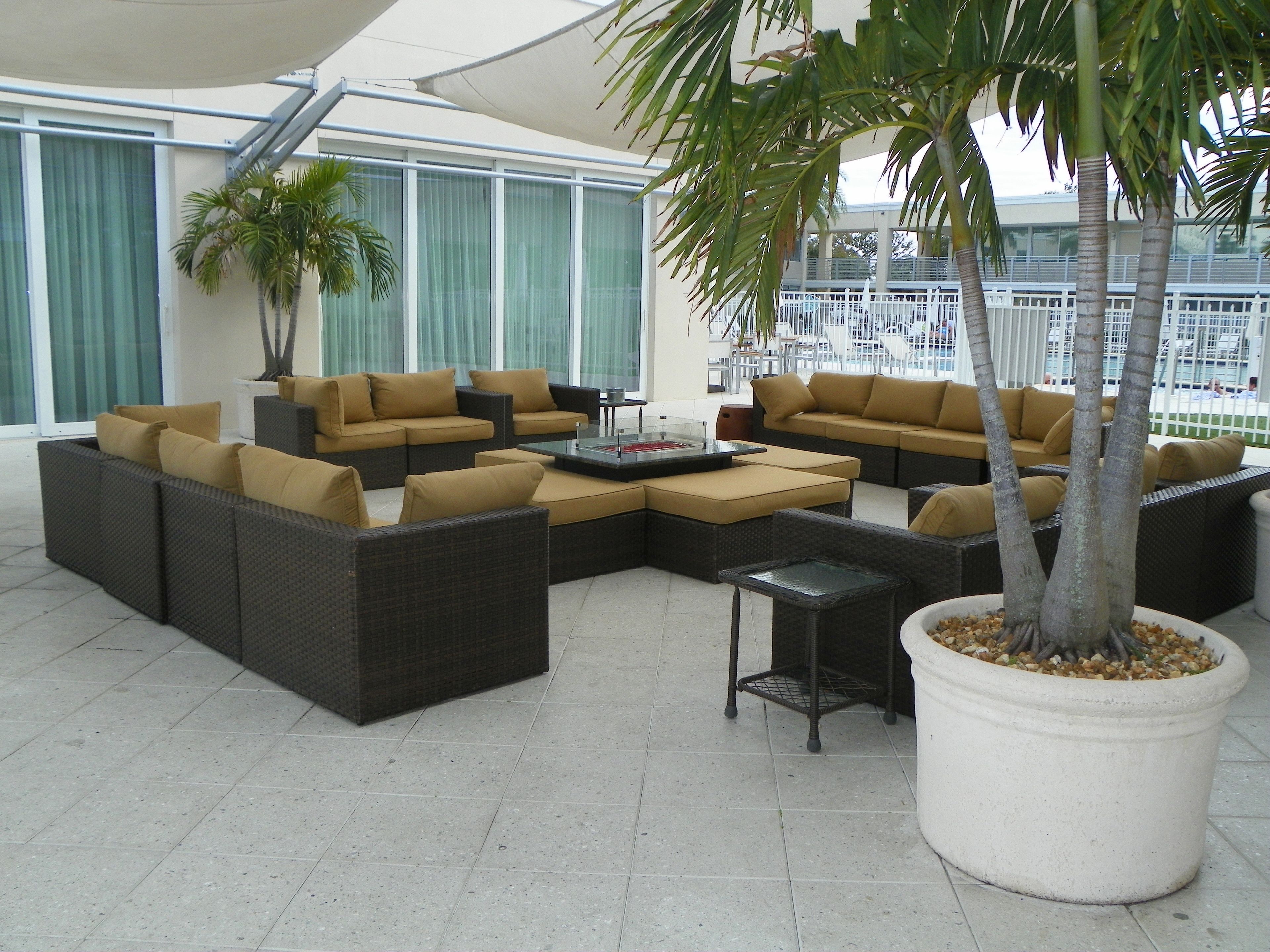 A modern outdoor seating area with wicker furniture and a large potted palm tree. - Ramada by Wyndham Venice Hotel Venezia (Venice)