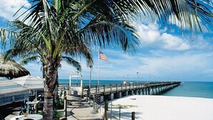 A beachside walkway with palm trees, a pier, and a flag. - Ramada by Wyndham Venice Hotel Venezia (Venice)