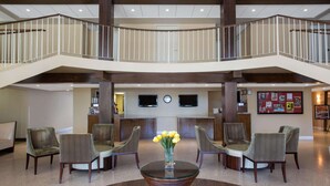 A lobby with a central glass table, four chairs, a clock, and a staircase. - Ramada by Wyndham Venice Hotel Venezia (Venice)