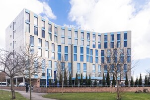 Un edificio moderno con un letrero que dice "PARK GRAND". Tiene fachada de ladrillo, varias ventanas y techo plano.