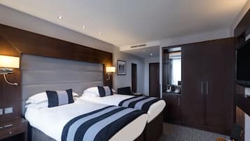 A hotel room with two beds, a desk, a TV, and a bathroom visible through an open door.