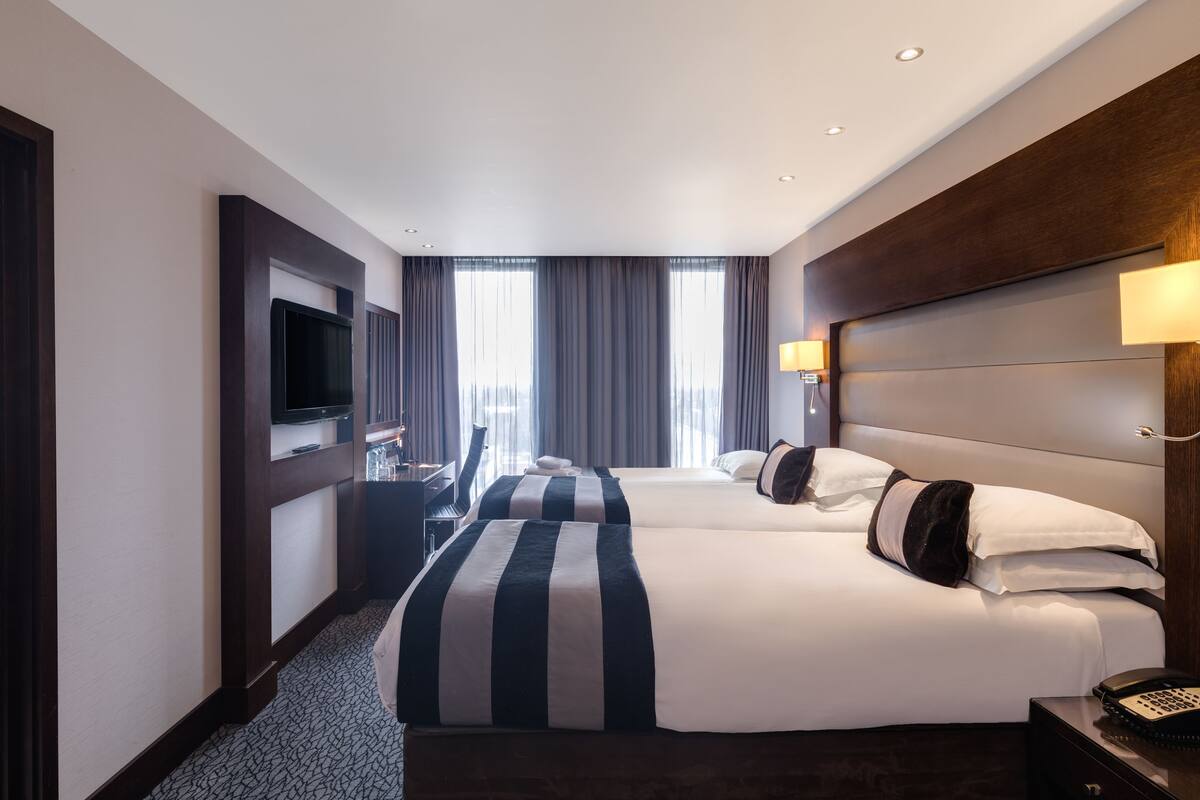 Een hotelkamer met twee bedden, een televisie, een bureau en een telefoon.