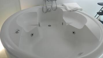 Una bañera blanca con ducha y una toalla al lado.