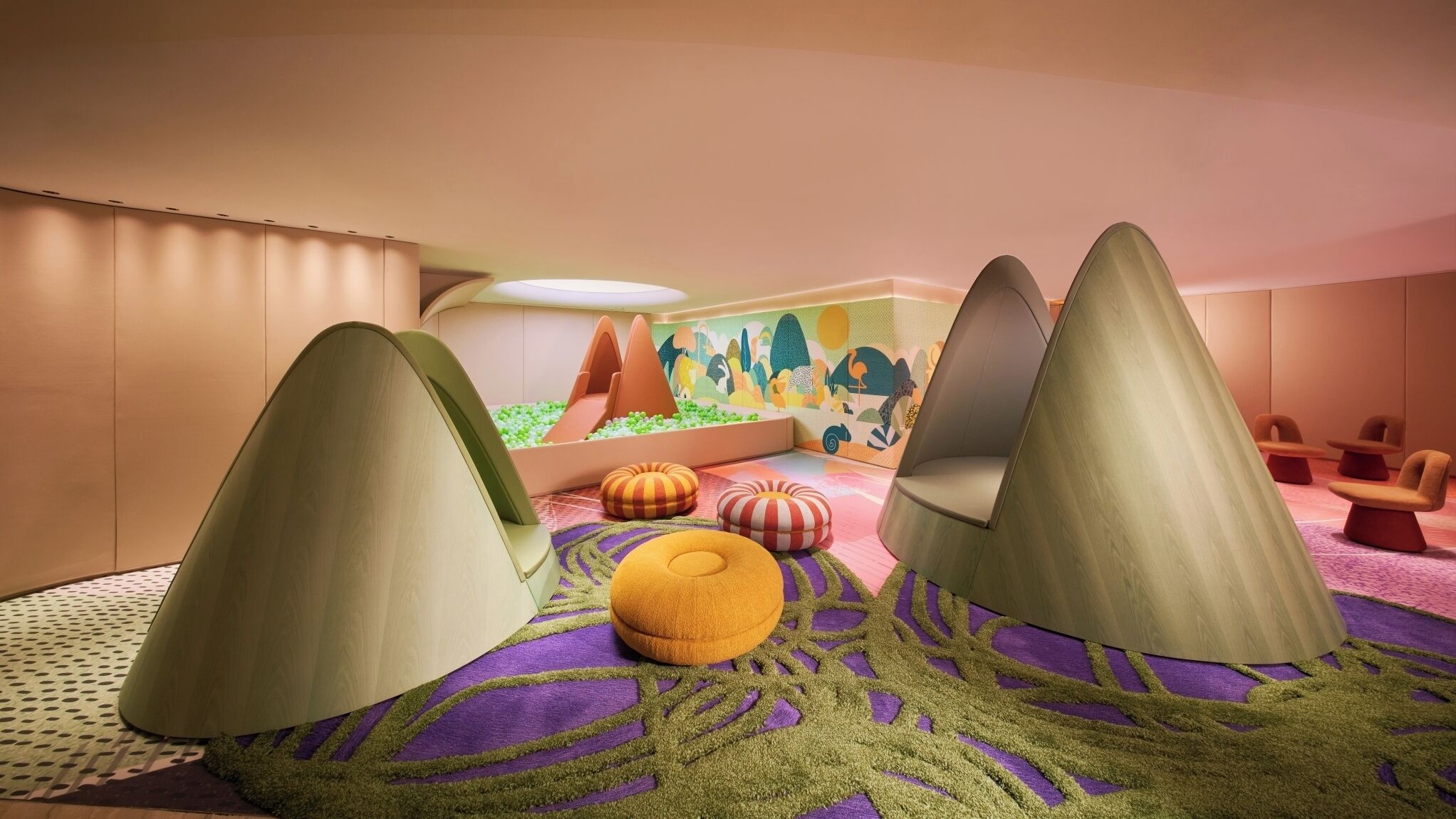 Un espace de jeux pour enfants avec des sièges confortables et une fresque murale colorée.
