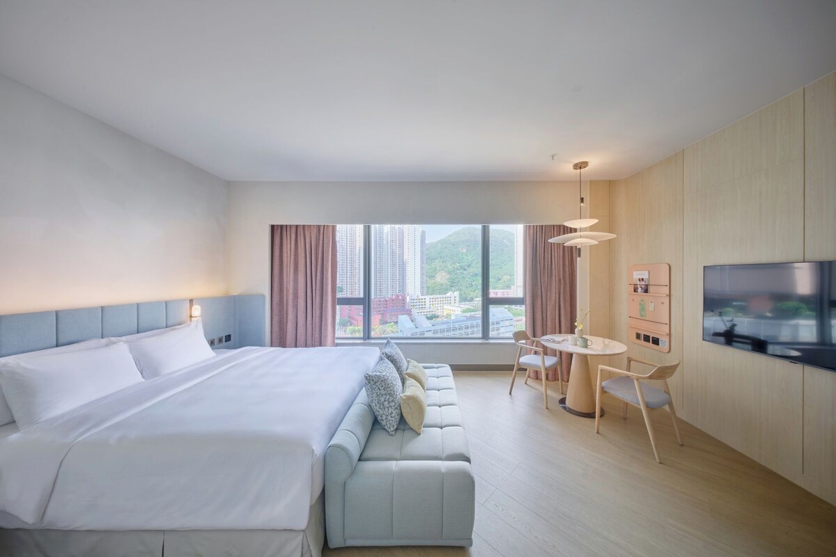 Habitación de hotel con una cama grande, un sofá, una mesa de comedor y una televisión.