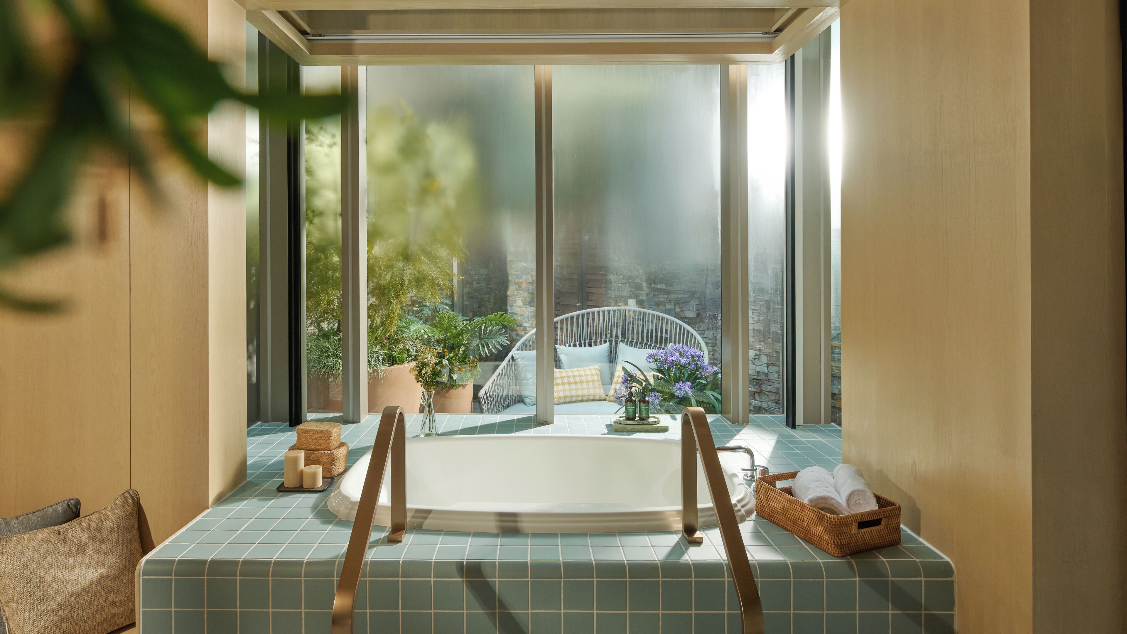 A bathroom with a bathtub, a window with a view of greenery, and a wicker basket with towels.