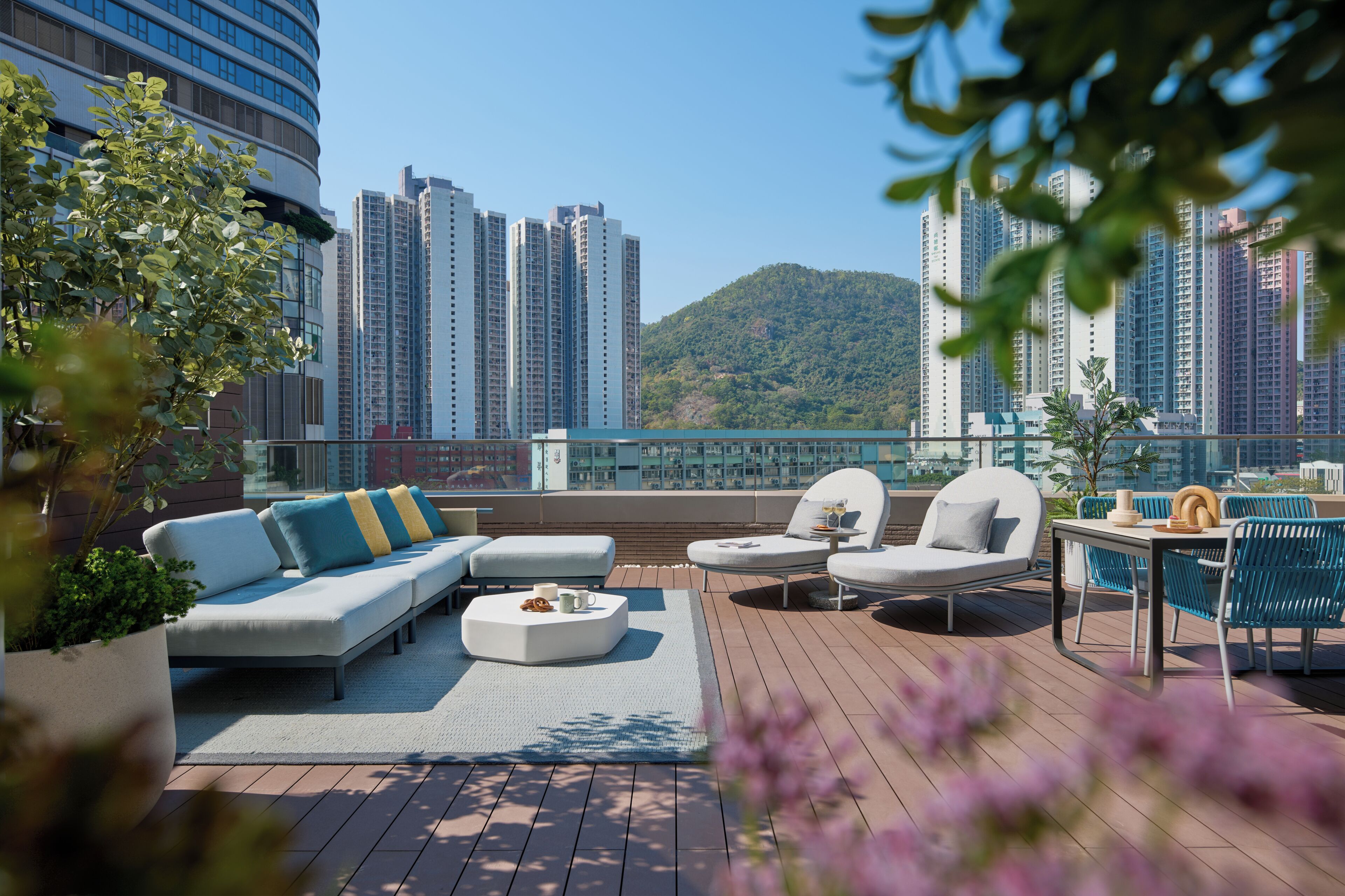 A rooftop terrace with a sofa, chairs, a table, and a potted plant.