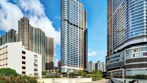 Un edificio alto con fachada curva, rodeado de otros edificios igualmente altos, bajo un cielo azul despejado.
