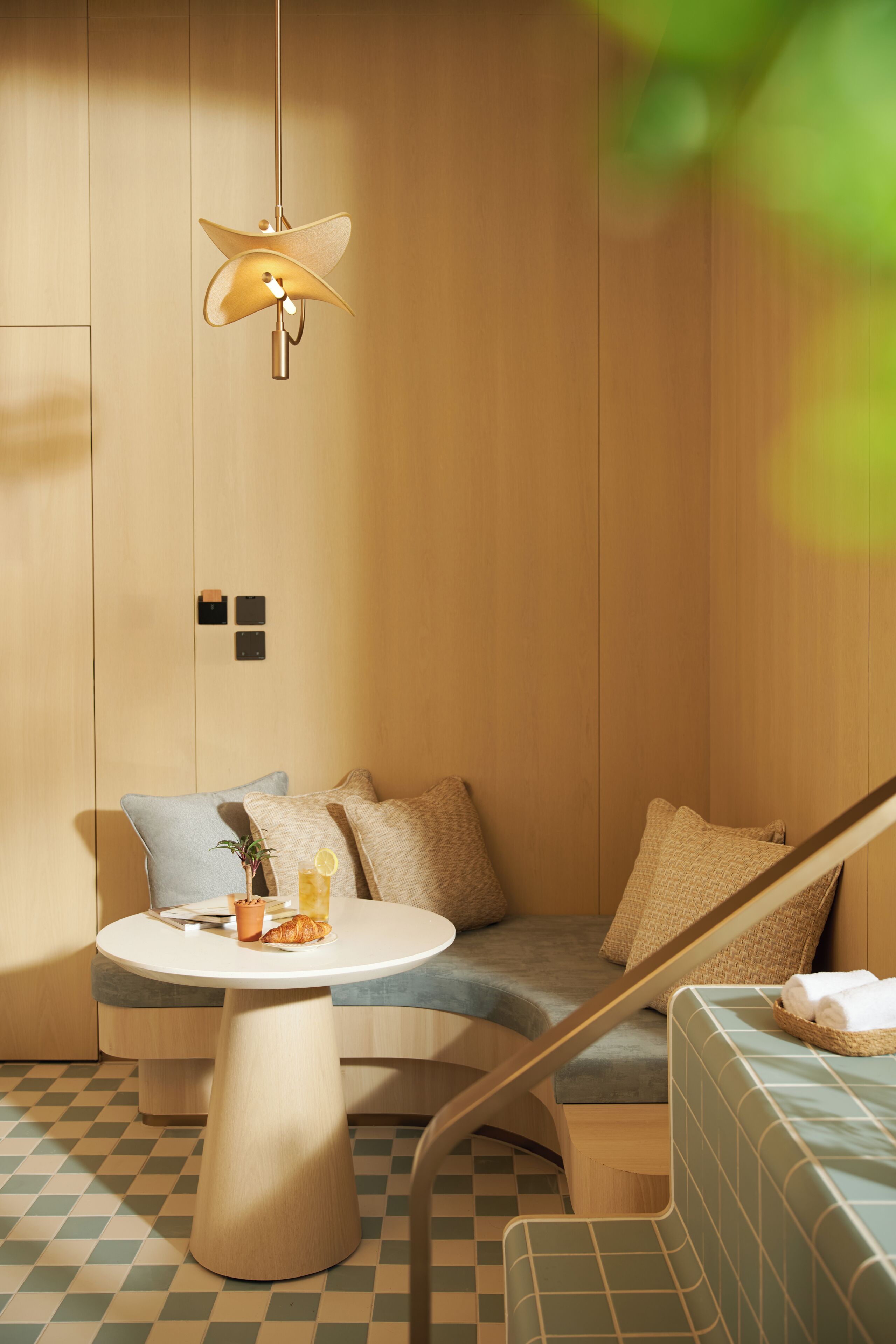 A modern room with a checkered floor, a round table, a sofa, and a hanging lamp.