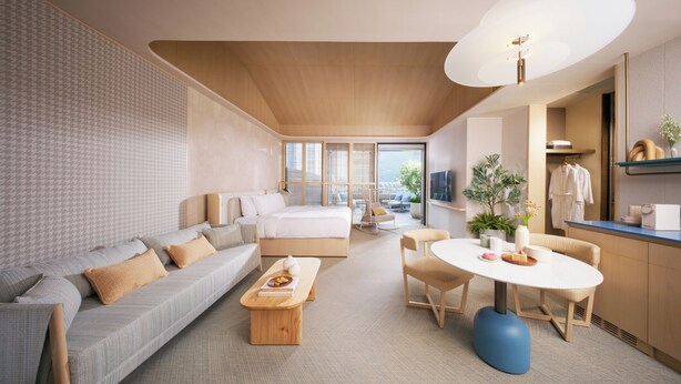 A modern hotel room with a large bed, a sofa, a dining table, and a small kitchen area. - The Royal Garden Kowloon East (Sai Kung)