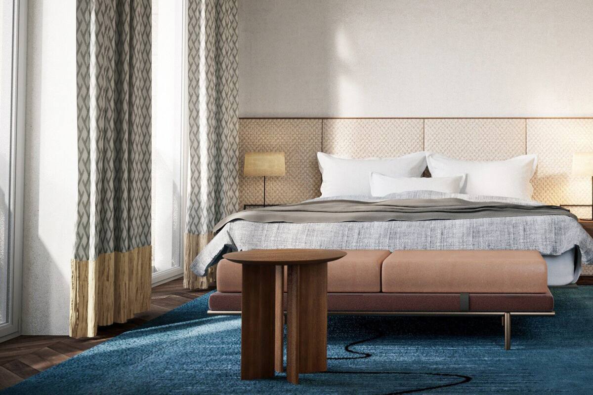 A modern hotel room with a large bed, a bedside table, and a view of the outdoors.