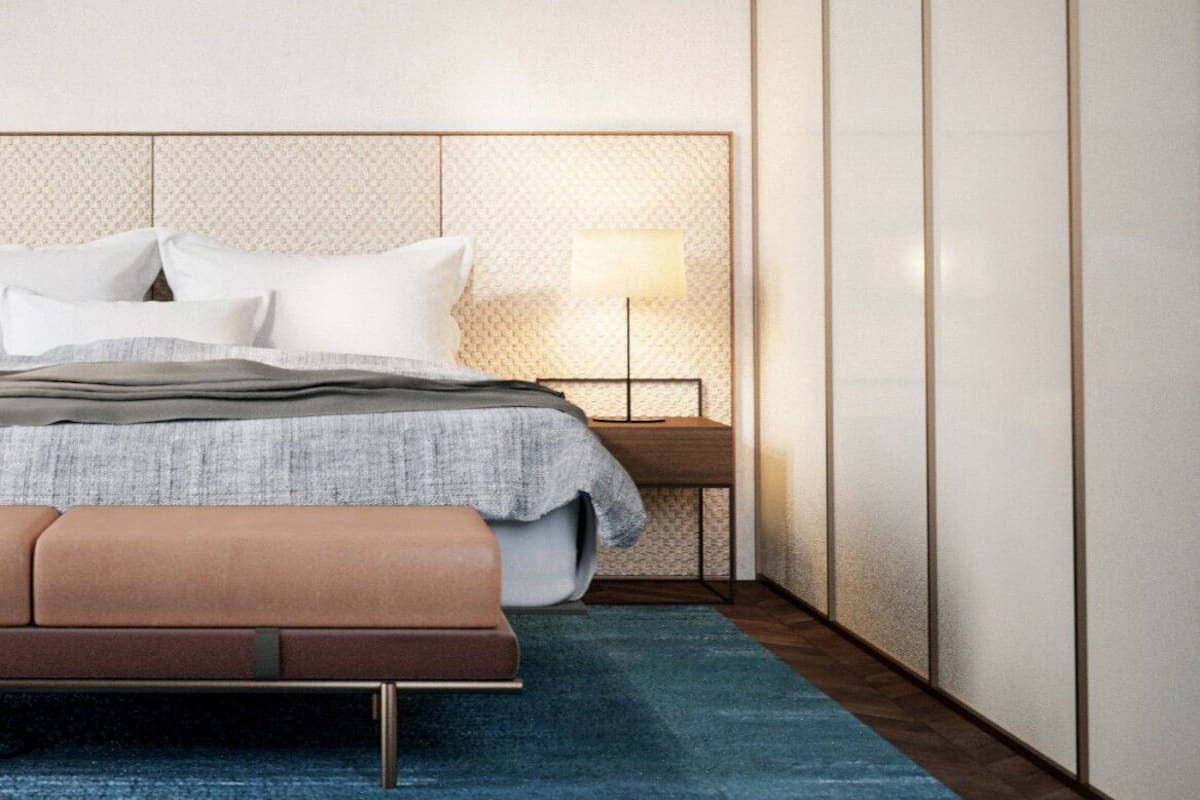 A modern bedroom with a bed, bedside table, lamp, and a bench.