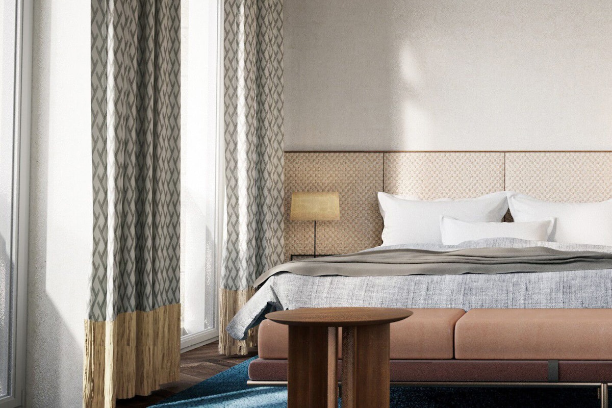 A hotel room with a bed, a nightstand, a lamp, and a window with curtains.