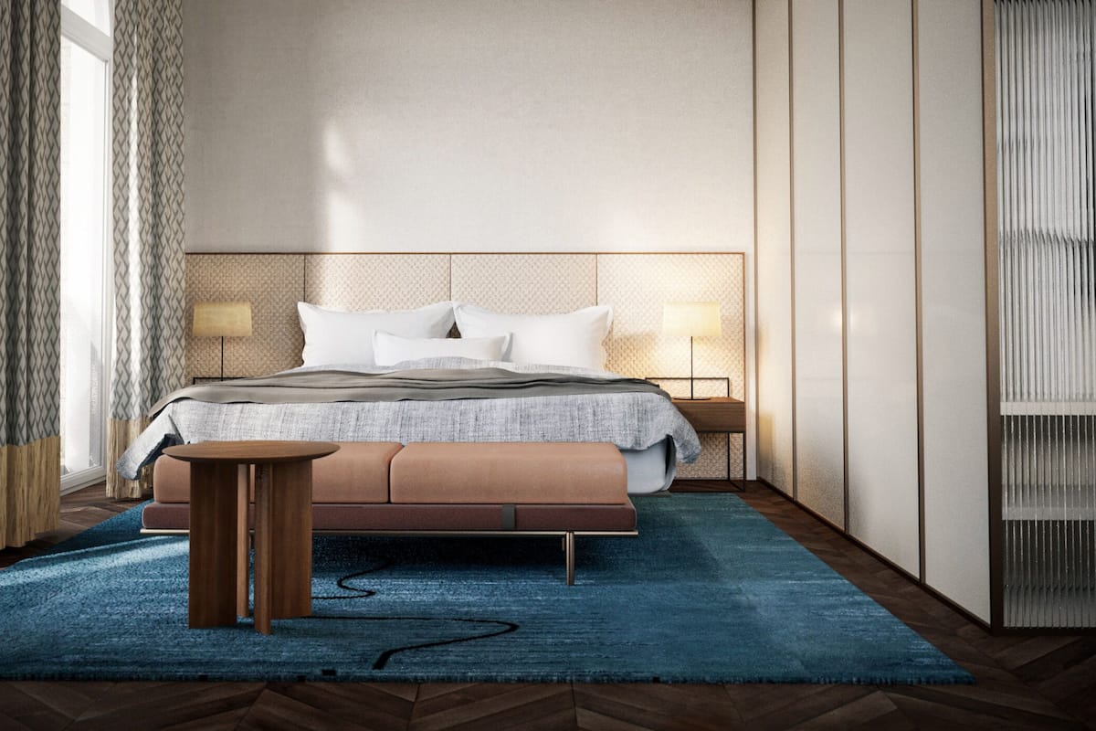 A modern bedroom with a large bed, bedside lamps, a wooden side table, and a blue rug.