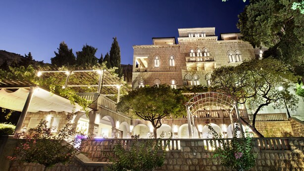 A historic building with multiple levels, stone walls, and a central staircase. - Villa Orsula (Dubrovnik)