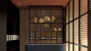 A modern reception area with a curved black bench, a display of bottles, and a wall with a grid pattern. - Villa Orsula (Dubrovnik)