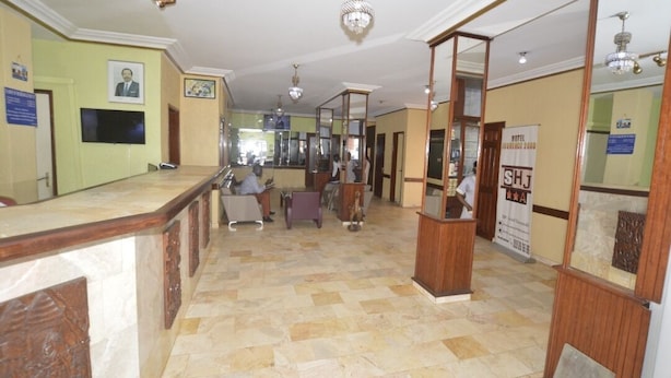 A hotel lobby with a reception desk, a check-in counter, and a waiting area with chairs. - Hotel Jouvence 2000 (Yaoundé)