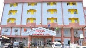 A multi-story hotel with a central entrance, multiple balconies, and a parking area in front. - Hotel Jouvence 2000 (Yaoundé)
