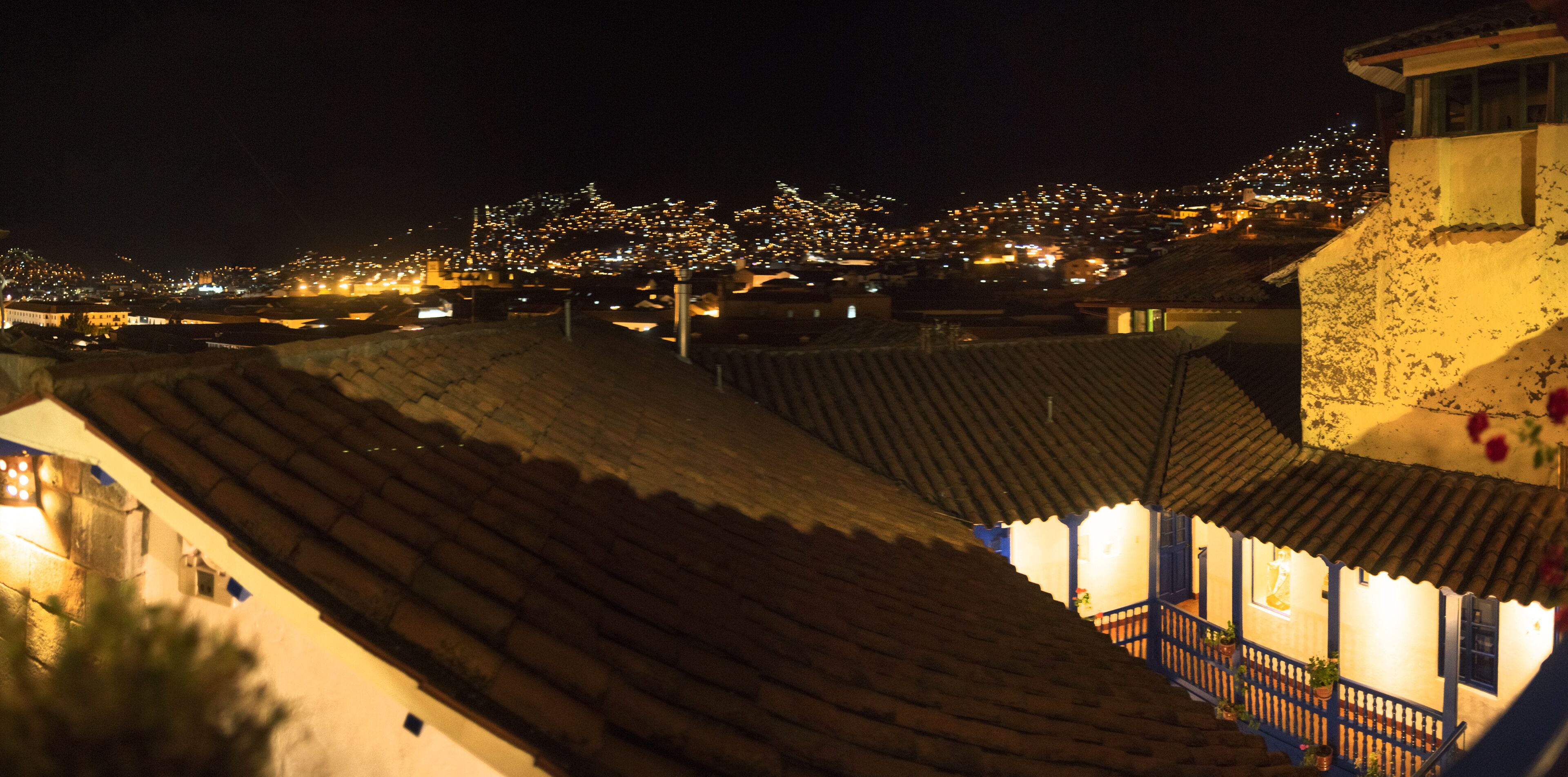 A night view of a town with illuminated buildings and a prominent hill in the background.