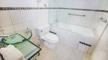 Un baño con cabina de ducha de vidrio, inodoro y lavamanos de vidrio.