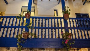 A blue balcony with stone walls and wooden beams, decorated with hanging planters and flowers. - Rumi Wasi (Cusco)