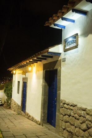 A building with a stone base and white upper walls, featuring a blue door and a sign above it.