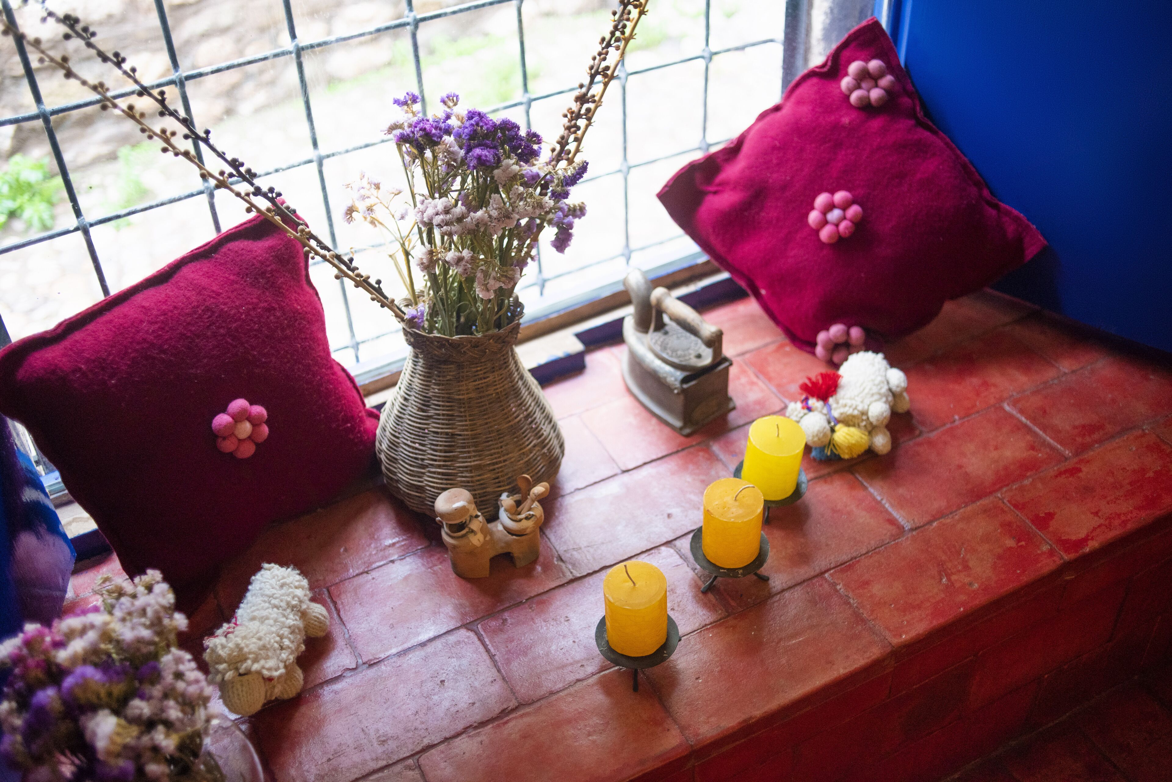 Ein Fensterplatz mit Blumen, Kerzen und dekorativen Kissen.