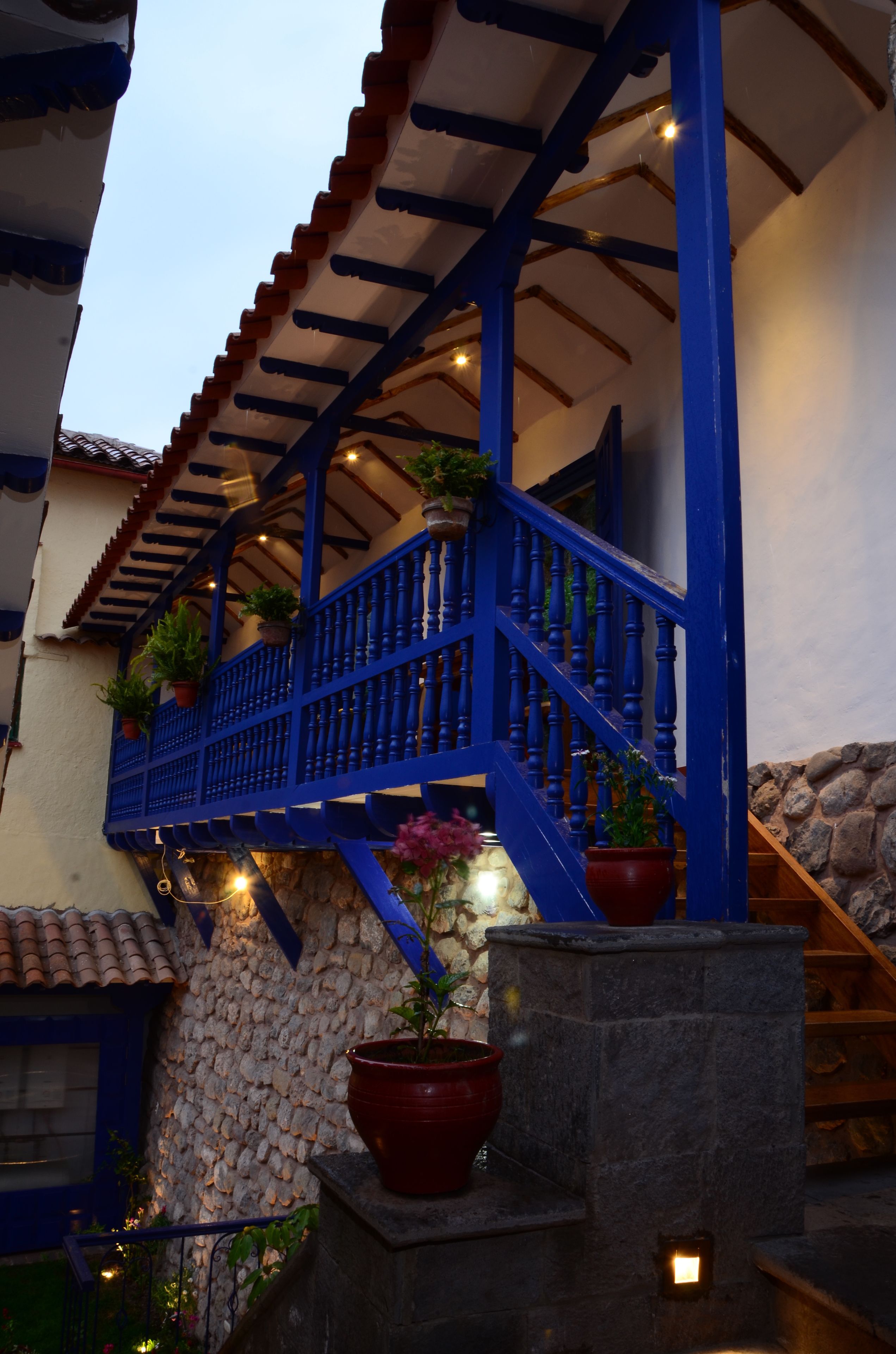 A blue staircase with potted plants, leading to a stone wall.