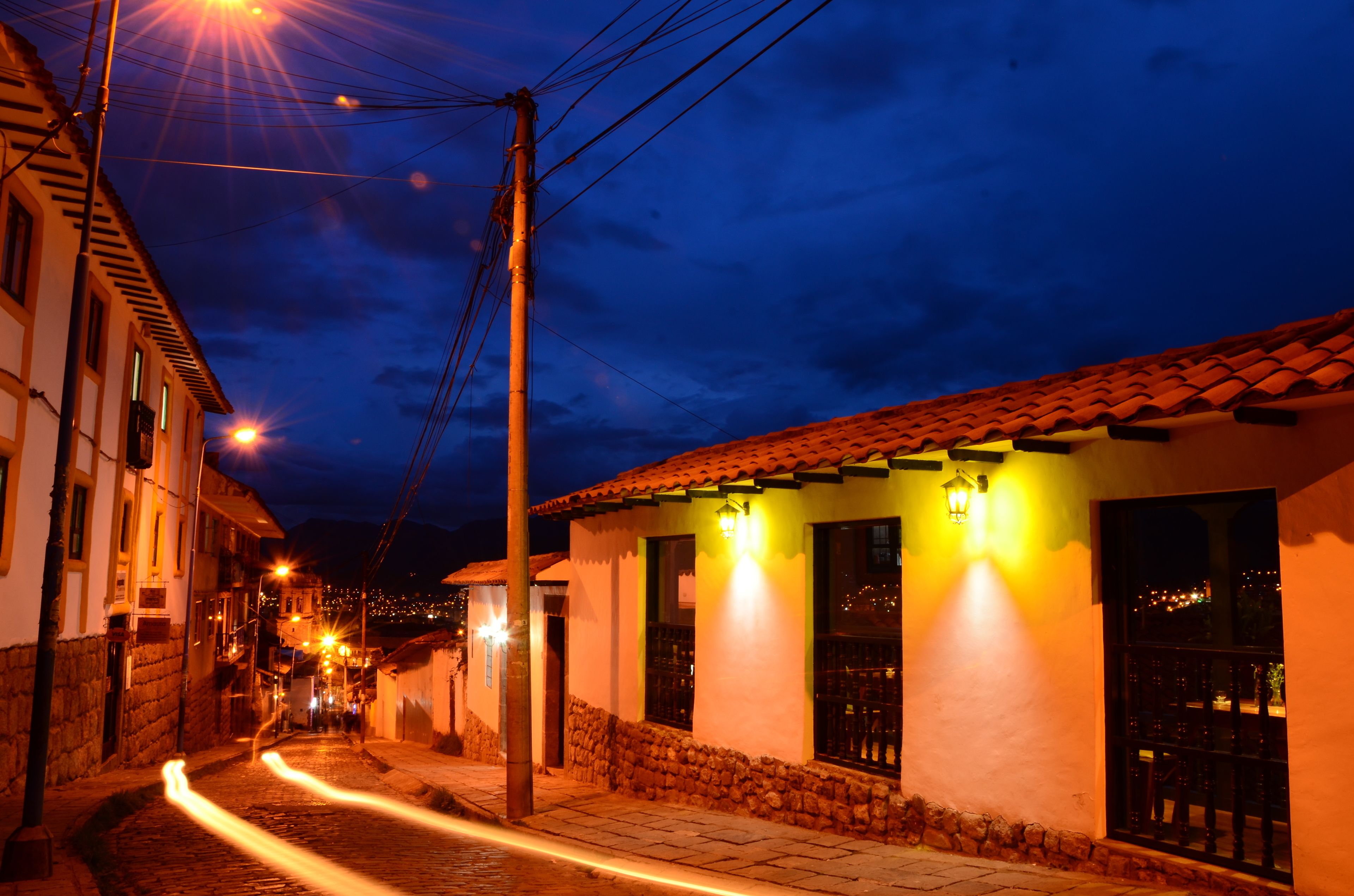 A narrow street at night with buildings on either side, illuminated by street lamps.