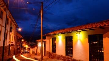 A narrow street at night with buildings on either side, illuminated by street lamps.