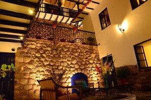 A stone wall with a blue door, a staircase with a railing, and potted plants. - Rumi Wasi (Cusco)