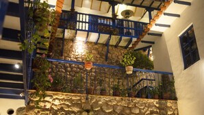A stone wall with a metal railing and potted plants. - Rumi Wasi (Cusco)