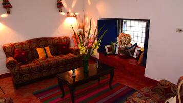 A living room with a patterned sofa, a coffee table, and a vase with flowers.