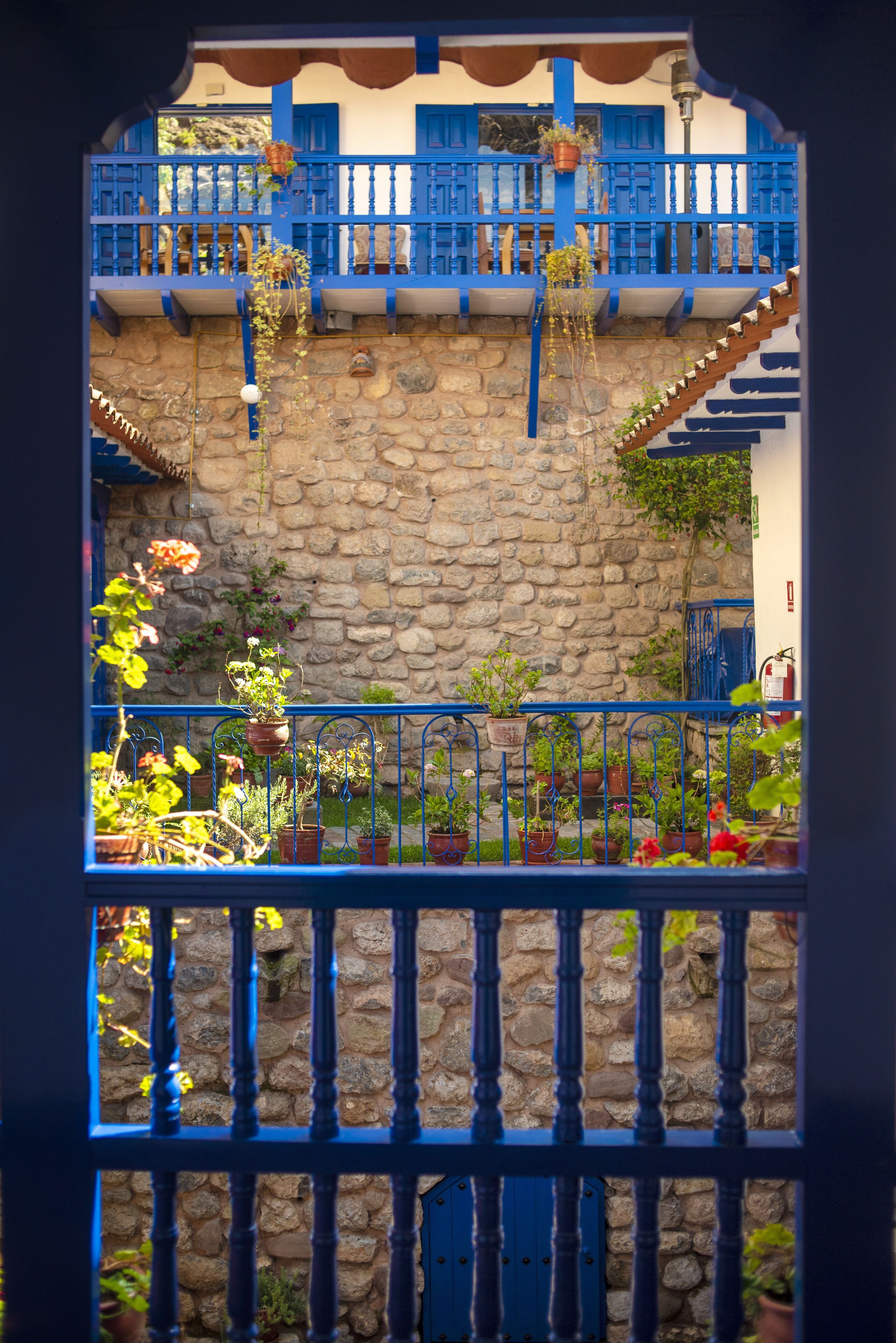 A stone wall with a blue railing and potted plants.