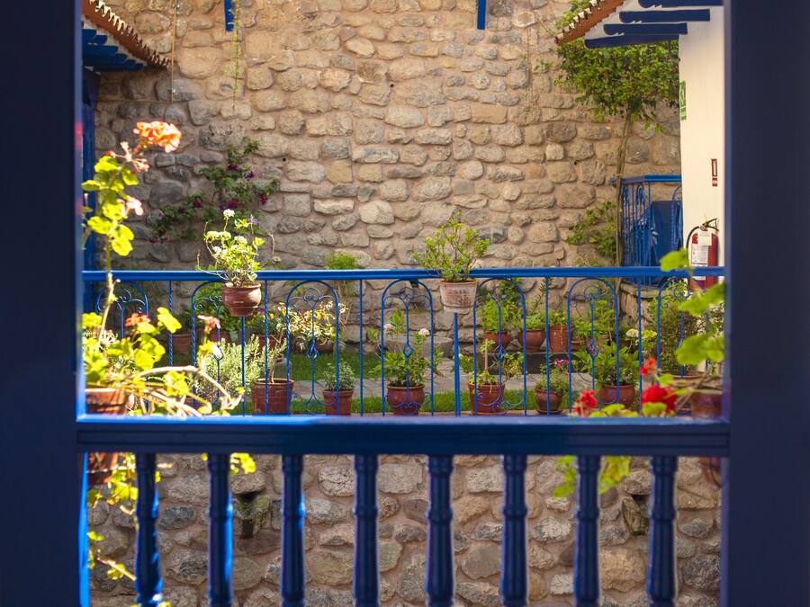 Pared de piedra con barandilla azul y plantas en macetas.