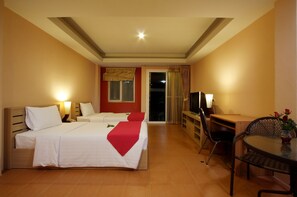 A hotel room with two beds, a desk, a chair, and a TV.